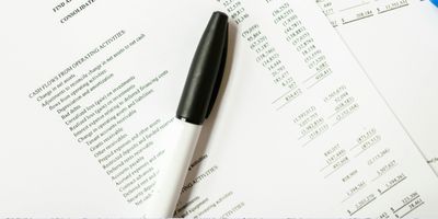 Printed out documents of business transaction history with a black permanent marker laying on top