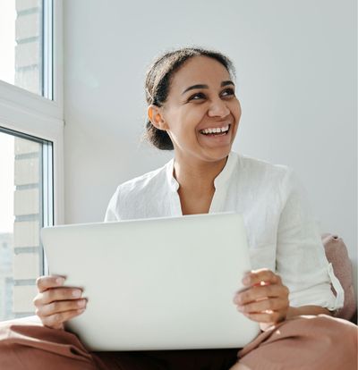 Happy woman with laptop who received assistance with sales tax from Your Accountant LLC