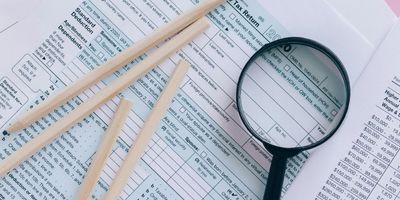 Form 1040 tax documents being inspected with a magnifying glass